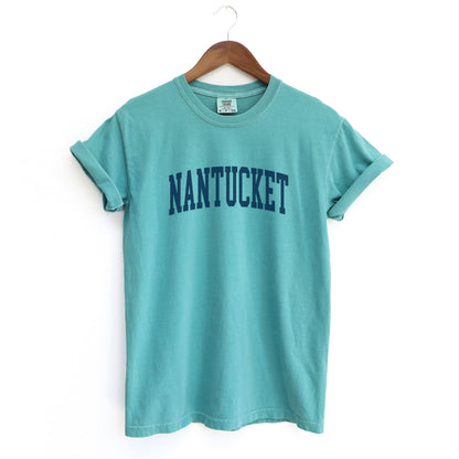 The Seafoam Adult Unisex Nantucket Massachusetts Varsity Comfort Colors T-shirt lays flat on a white background. The ﻿Nantucket Massachusetts Varsity﻿ graphic is in bold Navy in a Collegiate Block style.