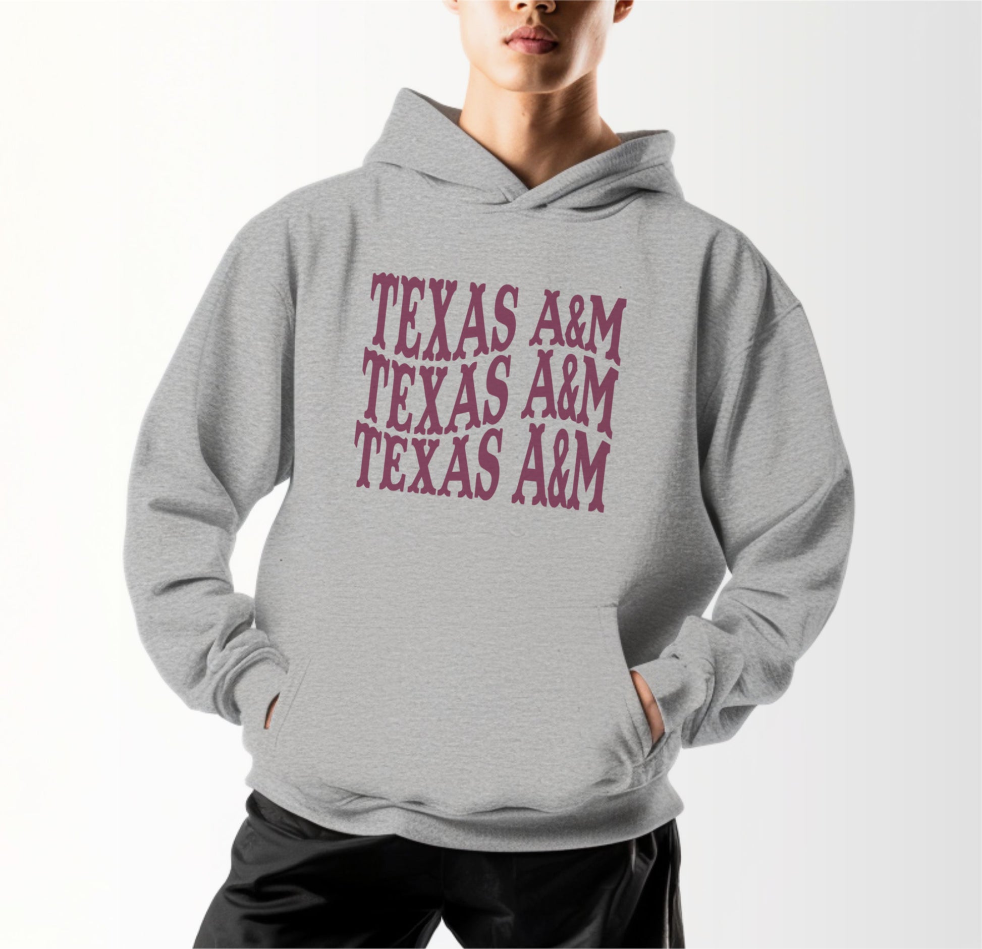 A model wears the Sport Grey Adult Unisex Texas A&M Western Hooded Sweatshirt.  The ﻿Texas A&M Western﻿ graphic is in bold Maroon in a Western style.