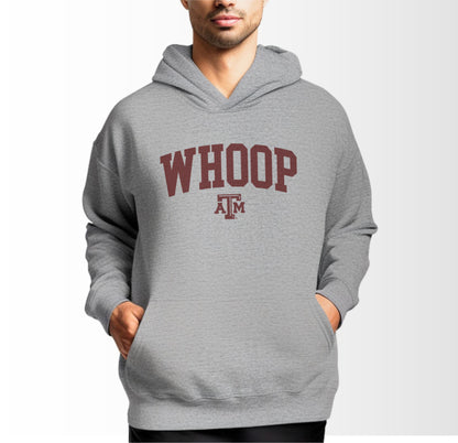 A model wears the Sport Grey Adult Unisex Texas A&M Whoop Collegiate Hooded Sweatshirt.  The ﻿Texas A&M Whoop Collegiate﻿ graphic is in bold Maroon in a Varsity style.