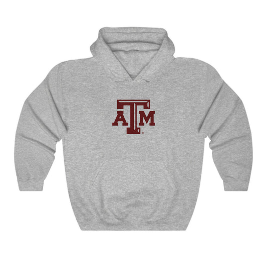 The Sport Grey Adult Unisex Texas A&M Logo Hooded Sweatshirt lays flat on a white background. The ﻿Texas A&M Logo﻿ graphic is in bold Maroon in a Varsity style.