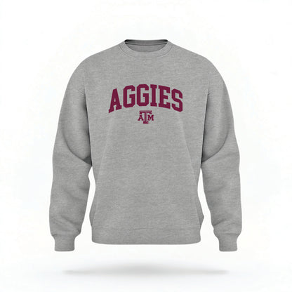 The Sport Grey Unisex Texas A&M Aggies Collegiate Crewneck Sweatshirt lays flat on a white background. The ﻿Texas A&M Aggies Collegiate﻿ graphic is in bold Maroon in a Collegiate style.