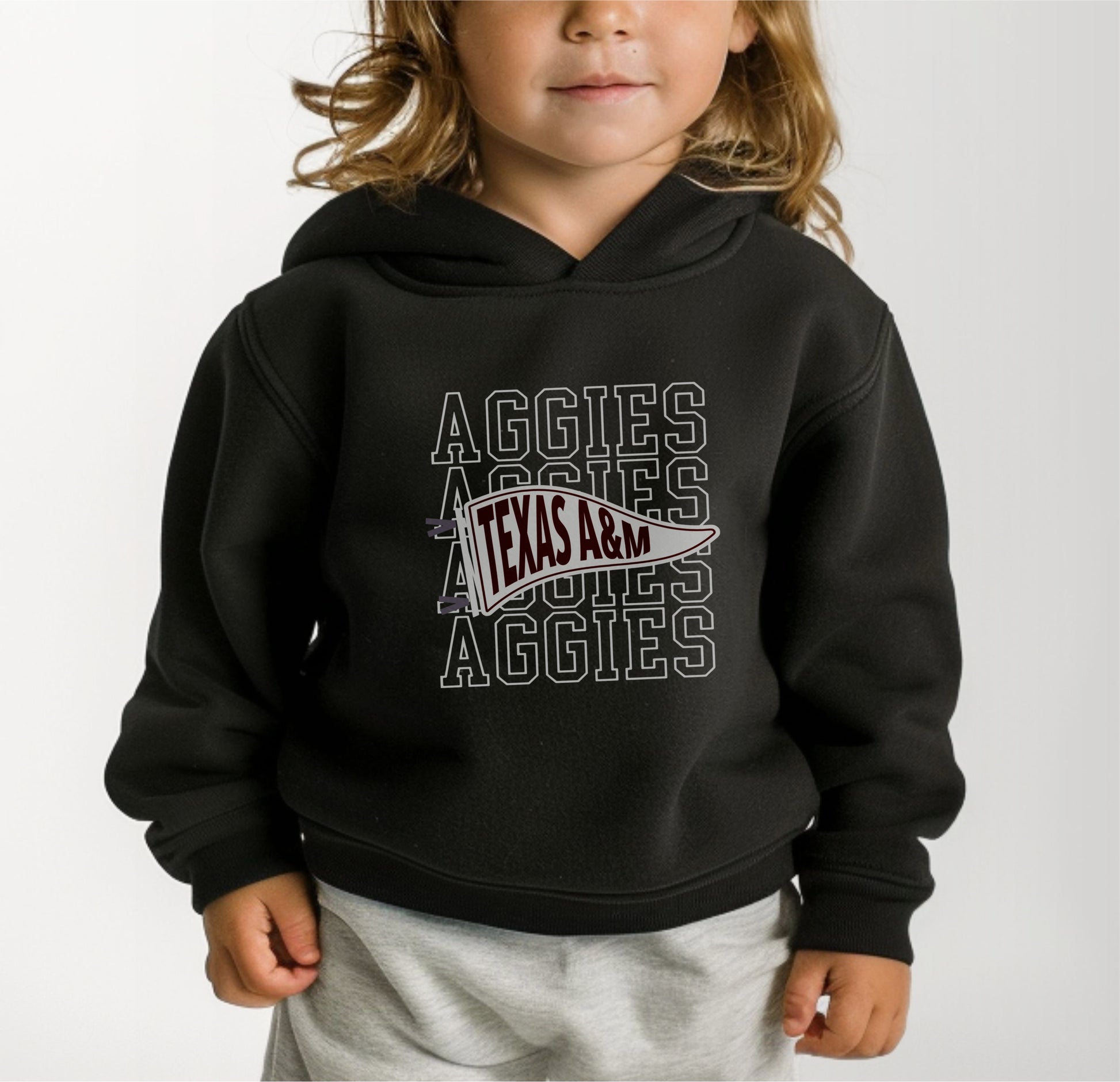 A model wears the Black Toddler Unisex Texas A&M Aggies Pennant Hooded Sweatshirt.  The ﻿Texas A&M Aggies Pennant﻿ graphic is in bold White in a Varsity style.