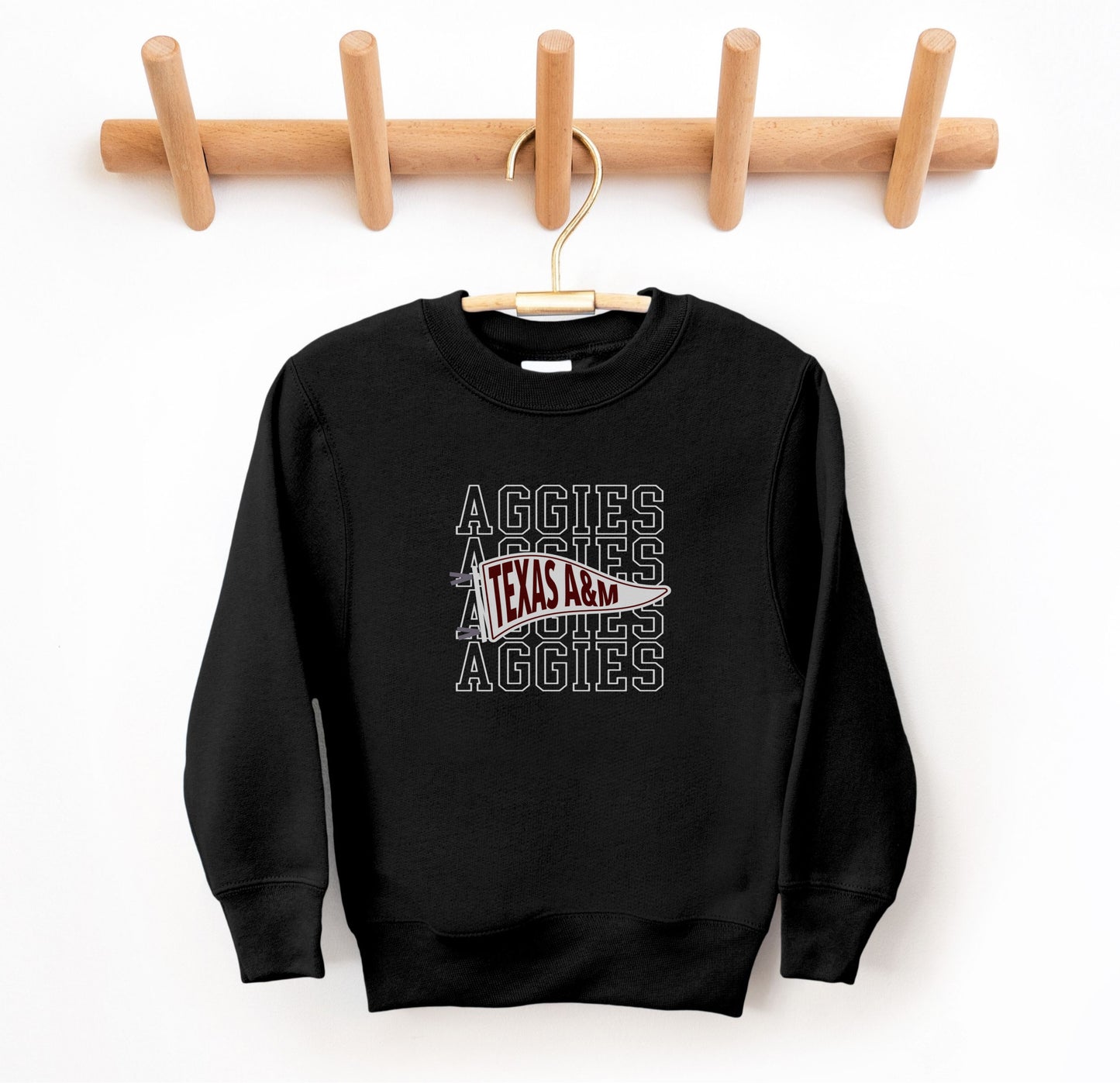 The Black Youth Unisex Texas A&M Aggies Pennant Crewneck Sweatshirt lays flat on a white background. The ﻿Texas A&M Aggies Pennant﻿ graphic is in bold White in a Varsity style.