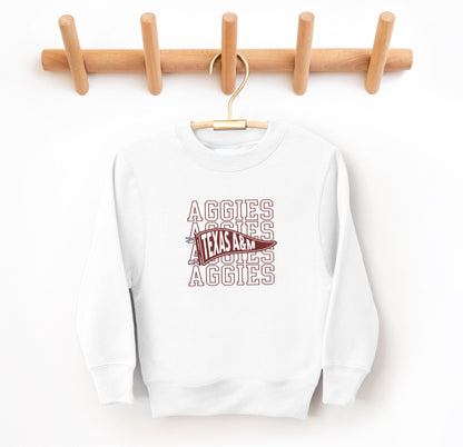 The White Youth Unisex Texas A&M Aggies Pennant Crewneck Sweatshirt lays flat on a white background. The ﻿Texas A&M Aggies Pennant﻿ graphic is in bold Maroon in a Varsity style.