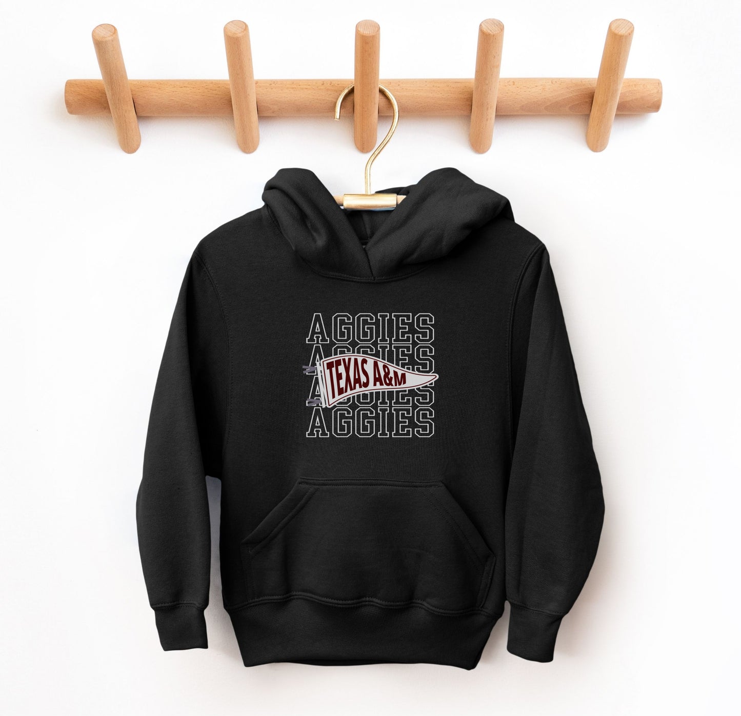 The Black Youth Unisex Texas A&M Aggies Pennant Hooded Sweatshirt lays flat on a white background. The ﻿Texas A&M Aggies Pennant﻿ graphic is in bold White in a Varsity style.