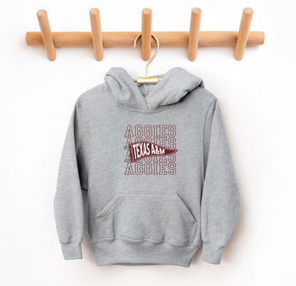 The Sport Grey Youth Unisex Texas A&M Aggies Pennant Hooded Sweatshirt lays flat on a white background. The ﻿Texas A&M Aggies Pennant﻿ graphic is in bold Maroon in a Varsity style.