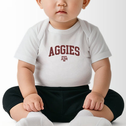 A model wears the White Infant Unisex Texas A&M Aggies Collegiate Bodysuit.  The ﻿Texas A&M Aggies Collegiate﻿ graphic is in bold Maroon in a Varsity style.