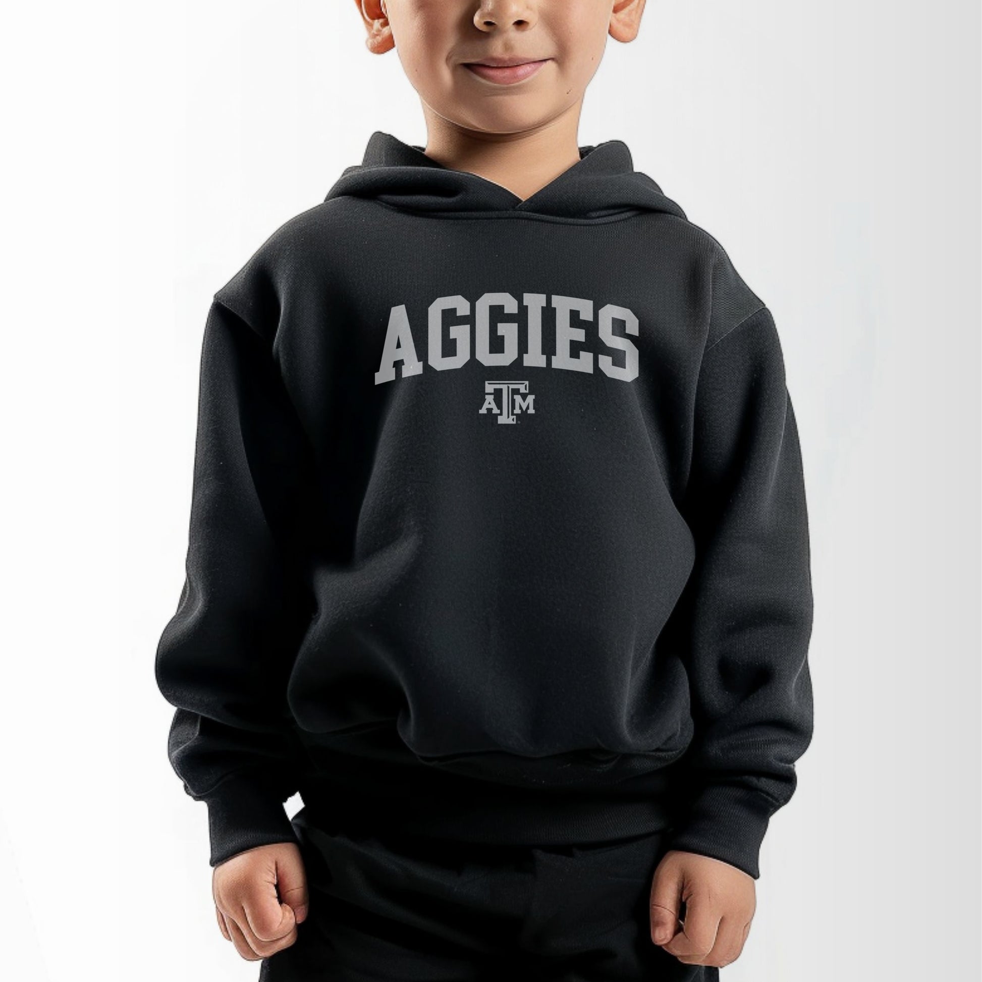 A model wears the Black Toddler Unisex Texas A&M Aggies Collegiate Hooded Sweatshirt.  The ﻿Texas A&M Aggies Collegiate﻿ graphic is in bold White in a Varsity style.