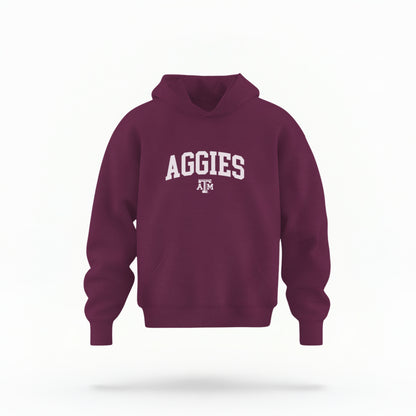 The Maroon Youth Unisex Texas A&M Aggies Collegiate Hooded Sweatshirt lays flat on a white background. The ﻿Texas A&M Aggies Collegiate﻿ graphic is in bold White in a Varsity style.