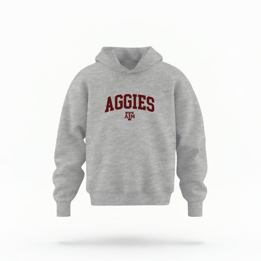 The Sport Grey Youth Unisex Texas A&M Aggies Collegiate Hooded Sweatshirt lays flat on a white background. The ﻿Texas A&M Aggies Collegiate﻿ graphic is in bold Maroon in a Varsity style.