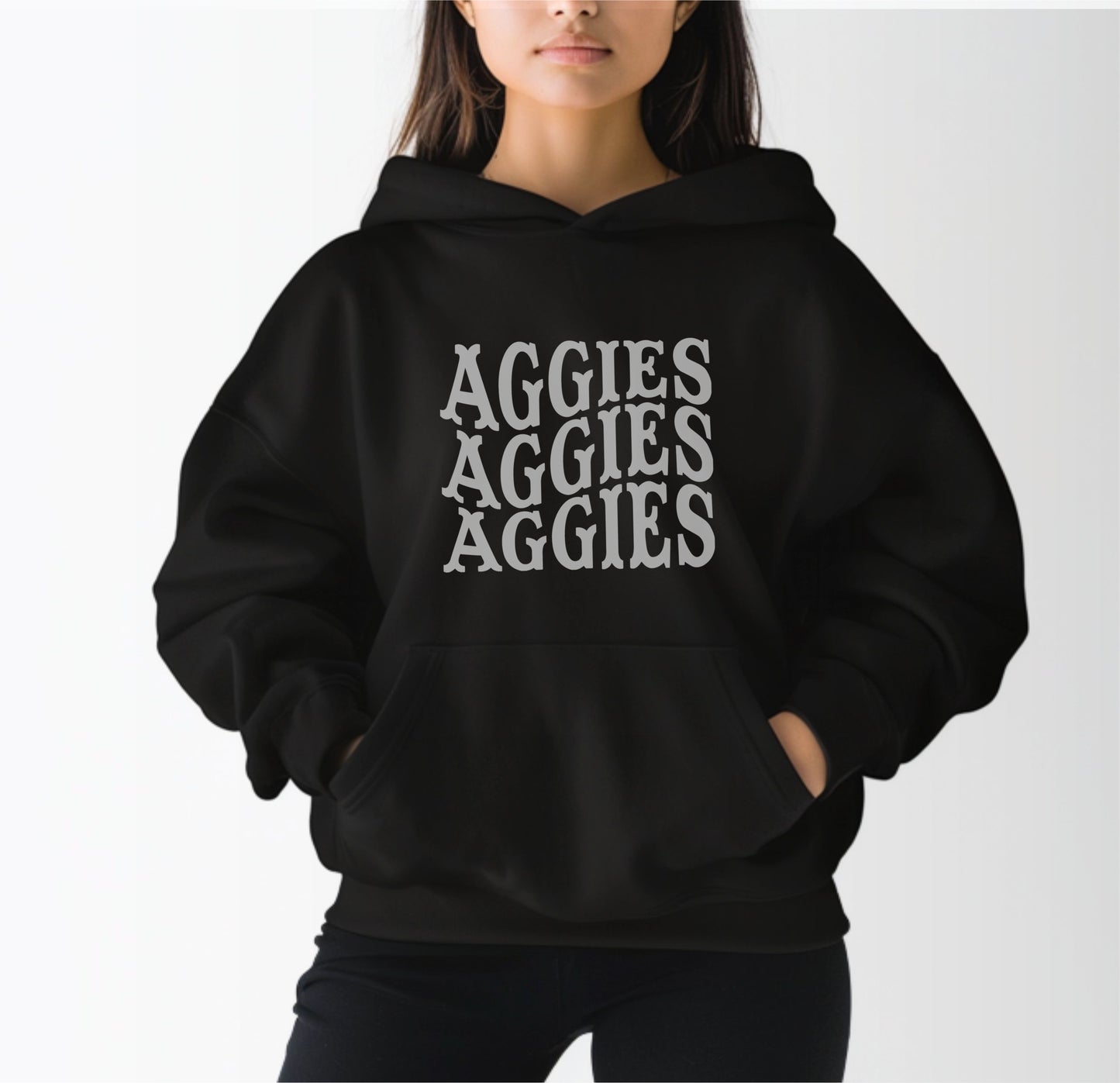 A model wears the Black Adult Unisex Texas A&M Aggies Aggies Aggies Western Hooded Sweatshirt.  The ﻿Texas A&M Aggies Aggies Aggies Western﻿ graphic is in bold Black in a Western style.