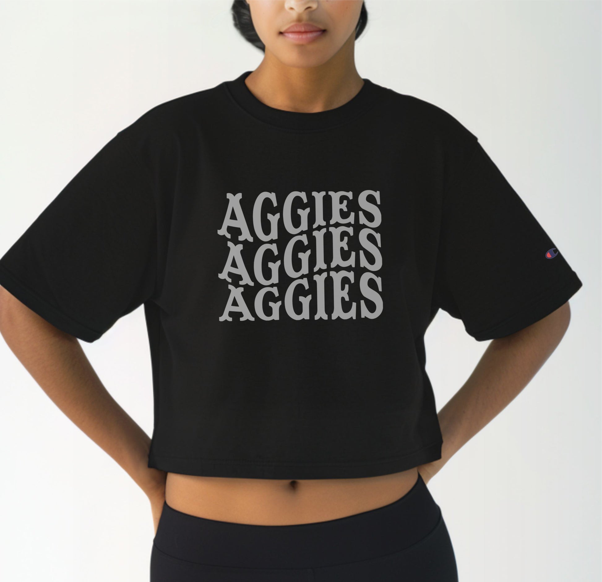 A model wears the Black Adult Womens Texas A&M Aggies Aggies Aggies Western Crop Top.  The ﻿Texas A&M Aggies Aggies Aggies Western﻿ graphic is in bold White in a Western style.