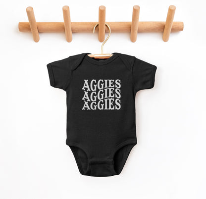 The Black Infant Unisex Texas A&M Aggies Aggies Aggies Western Bodysuit lays flat on a white background. The ﻿Texas A&M Aggies Aggies Aggies Western﻿ graphic is in bold White in a Western style.