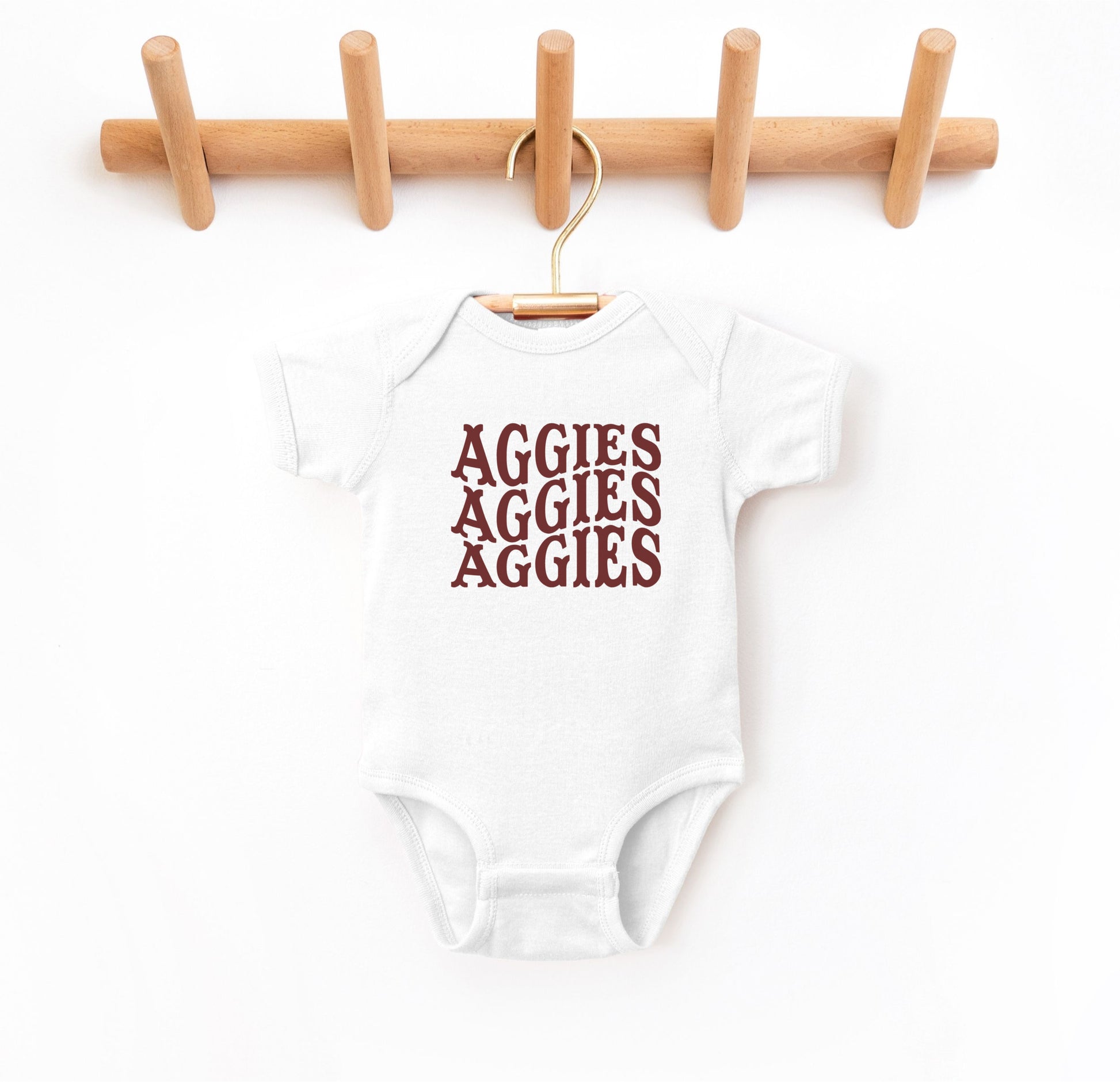 The White Infant Unisex Texas A&M Aggies Aggies Aggies Western Bodysuit lays flat on a white background. The ﻿Texas A&M Aggies Aggies Aggies Western﻿ graphic is in bold Maroon in a Western style.