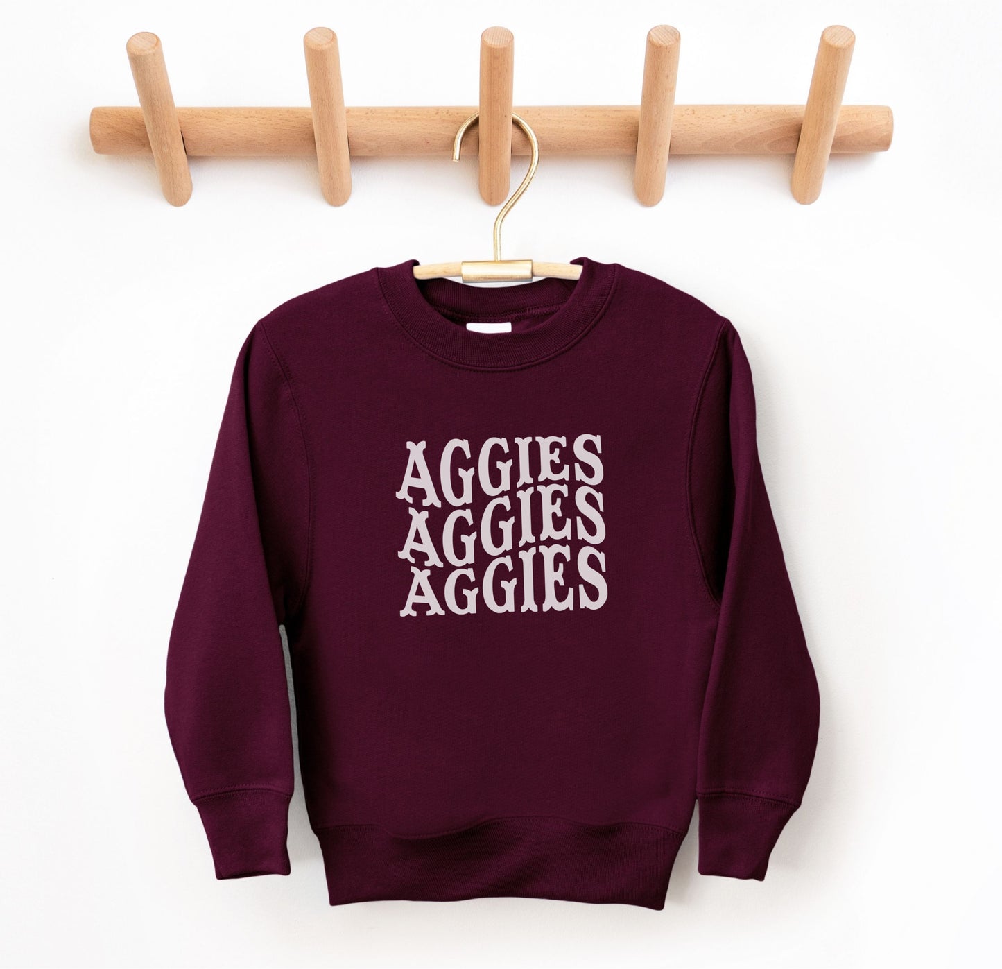 The Maroon Youth Unisex Texas A&M Aggies Aggies Aggies Western Crewneck Sweatshirt lays flat on a white background. The ﻿Texas A&M Aggies Aggies Aggies Western﻿ graphic is in bold White in a Western style.