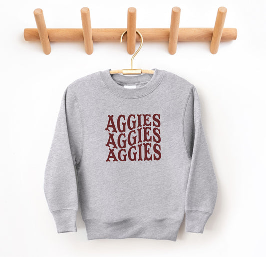 The Sport Grey Youth Unisex Texas A&M Aggies Aggies Aggies Western Crewneck Sweatshirt lays flat on a white background. The ﻿Texas A&M Aggies Aggies Aggies Western﻿ graphic is in bold Maroon in a Western style.