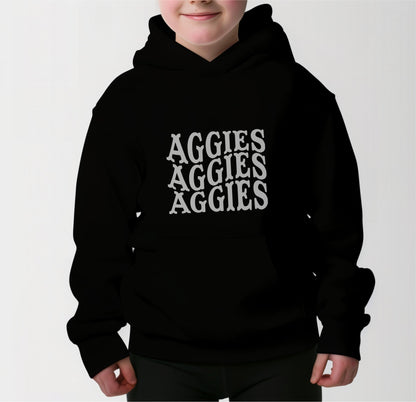 A model wears the Black Youth Unisex Texas A&M Aggies Aggies Aggies Western Hooded Sweatshirt.  The ﻿Texas A&M Aggies Aggies Aggies Western﻿ graphic is in bold White in a Western style.