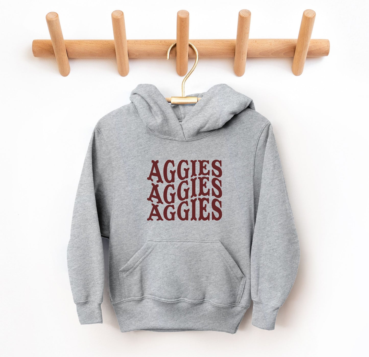 The Sport Grey Youth Unisex Texas A&M Aggies Aggies Aggies Western Hooded Sweatshirt lays flat on a white background. The ﻿Texas A&M Aggies Aggies Aggies Western﻿ graphic is in bold Maroon in a Western style.