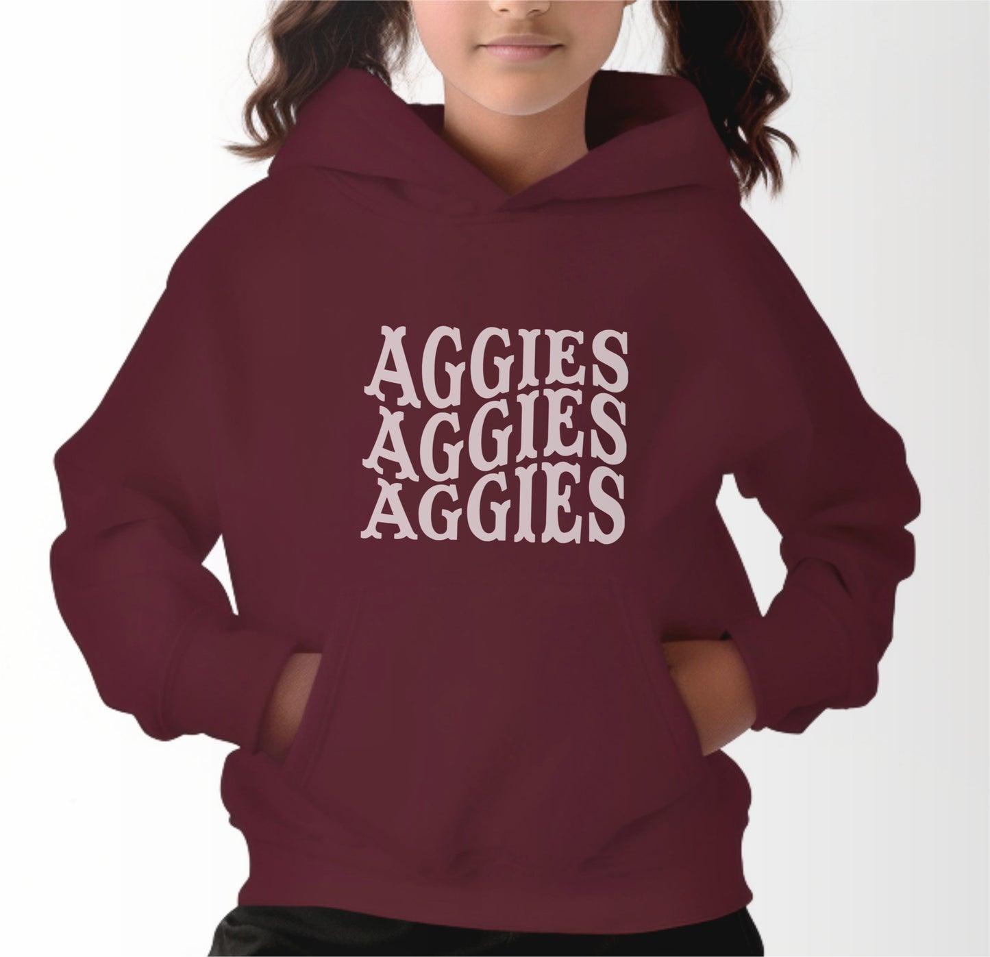 A model wears the Maroon Youth Unisex Texas A&M Aggies Aggies Aggies Western Hooded Sweatshirt.  The ﻿Texas A&M Aggies Aggies Aggies Western﻿ graphic is in bold White in a Western style.