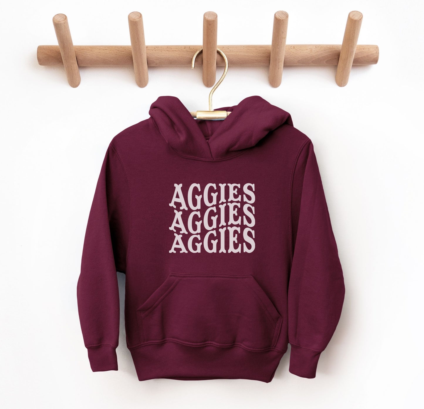 The Maroon Youth Unisex Texas A&M Aggies Aggies Aggies Western Hooded Sweatshirt lays flat on a white background. The ﻿Texas A&M Aggies Aggies Aggies Western﻿ graphic is in bold White in a Western style.