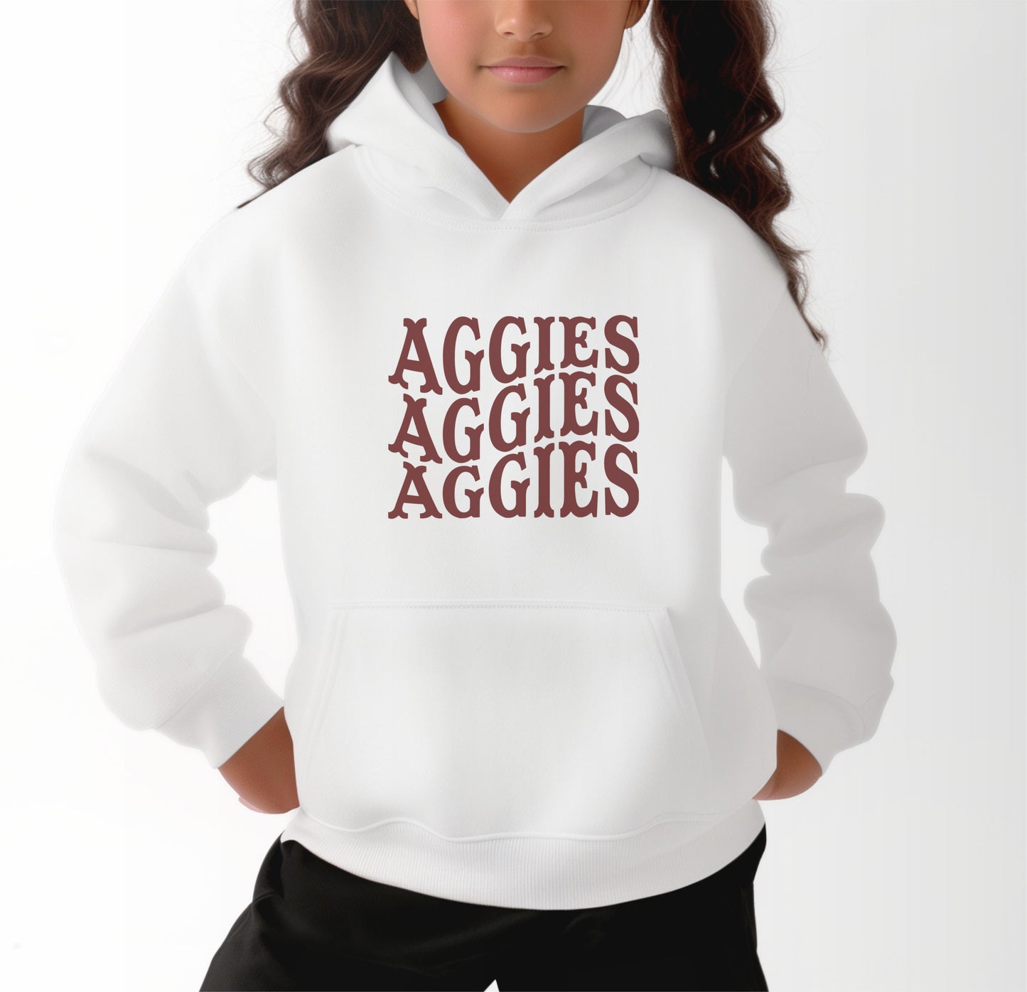 A model wears the White Youth Unisex Texas A&M Aggies Aggies Aggies Western Hooded Sweatshirt.  The ﻿Texas A&M Aggies Aggies Aggies Western﻿ graphic is in bold Maroon in a Western style.