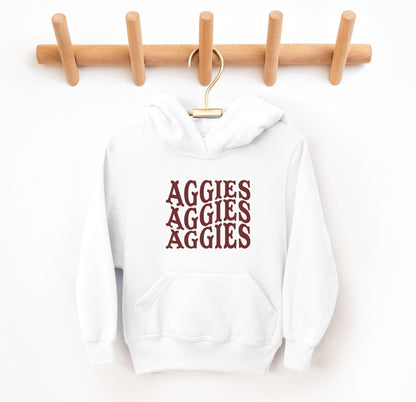 The White Youth Unisex Texas A&M Aggies Aggies Aggies Western Hooded Sweatshirt lays flat on a white background. The ﻿Texas A&M Aggies Aggies Aggies Western﻿ graphic is in bold Maroon in a Western style.