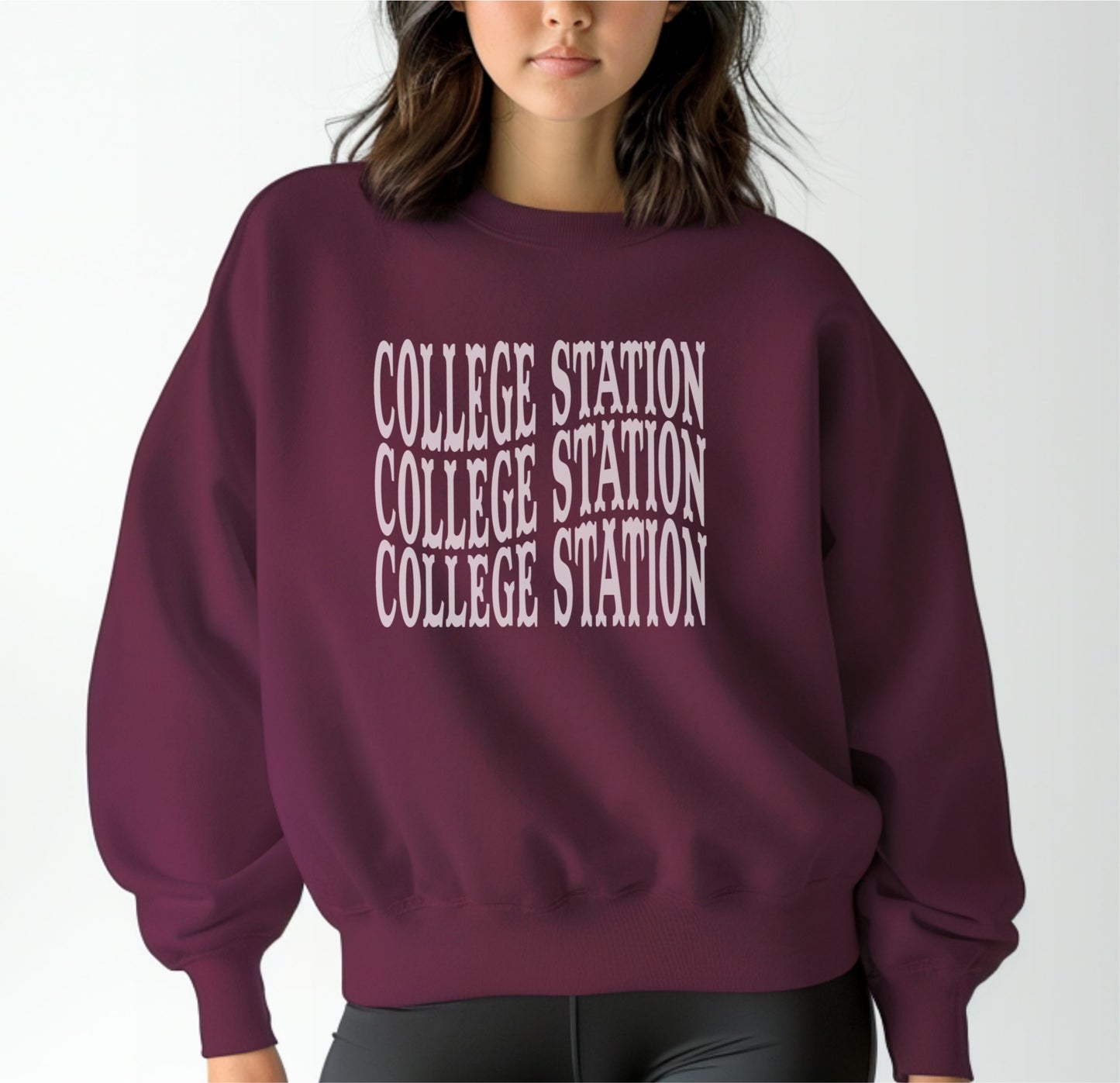 A model wears the Maroon Adult Unisex College Station Western Crewneck Sweatshirt.  The ﻿College Station Western﻿ graphic is in bold White in a Western style.