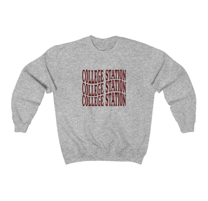 The Sport Grey Adult Unisex College Station Western Crewneck Sweatshirt lays flat on a white background. The ﻿College Station Western﻿ graphic is in bold Maroon in a Western style.