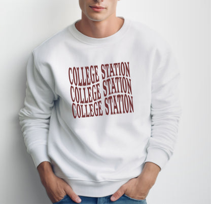 A model wears the White Adult Unisex College Station Western Crewneck Sweatshirt.  The ﻿College Station Western﻿ graphic is in bold Maroon in a Western style.