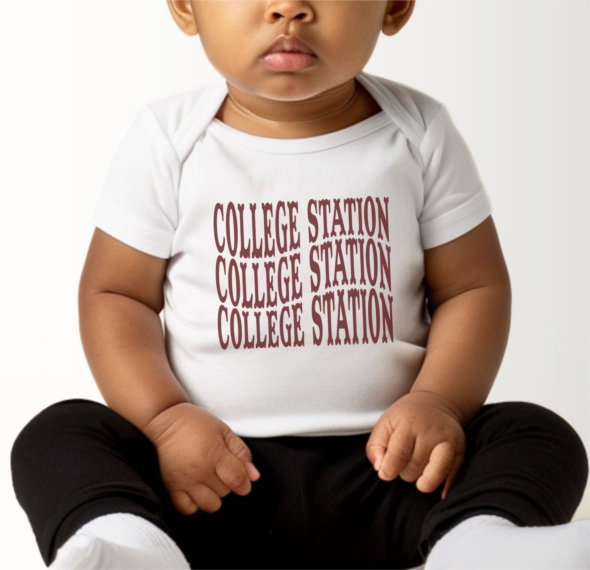 A model wears the White Infant Unisex College Station Western Bodysuit.  The ﻿College Station Western﻿ graphic is in bold Maroon in a Western style.