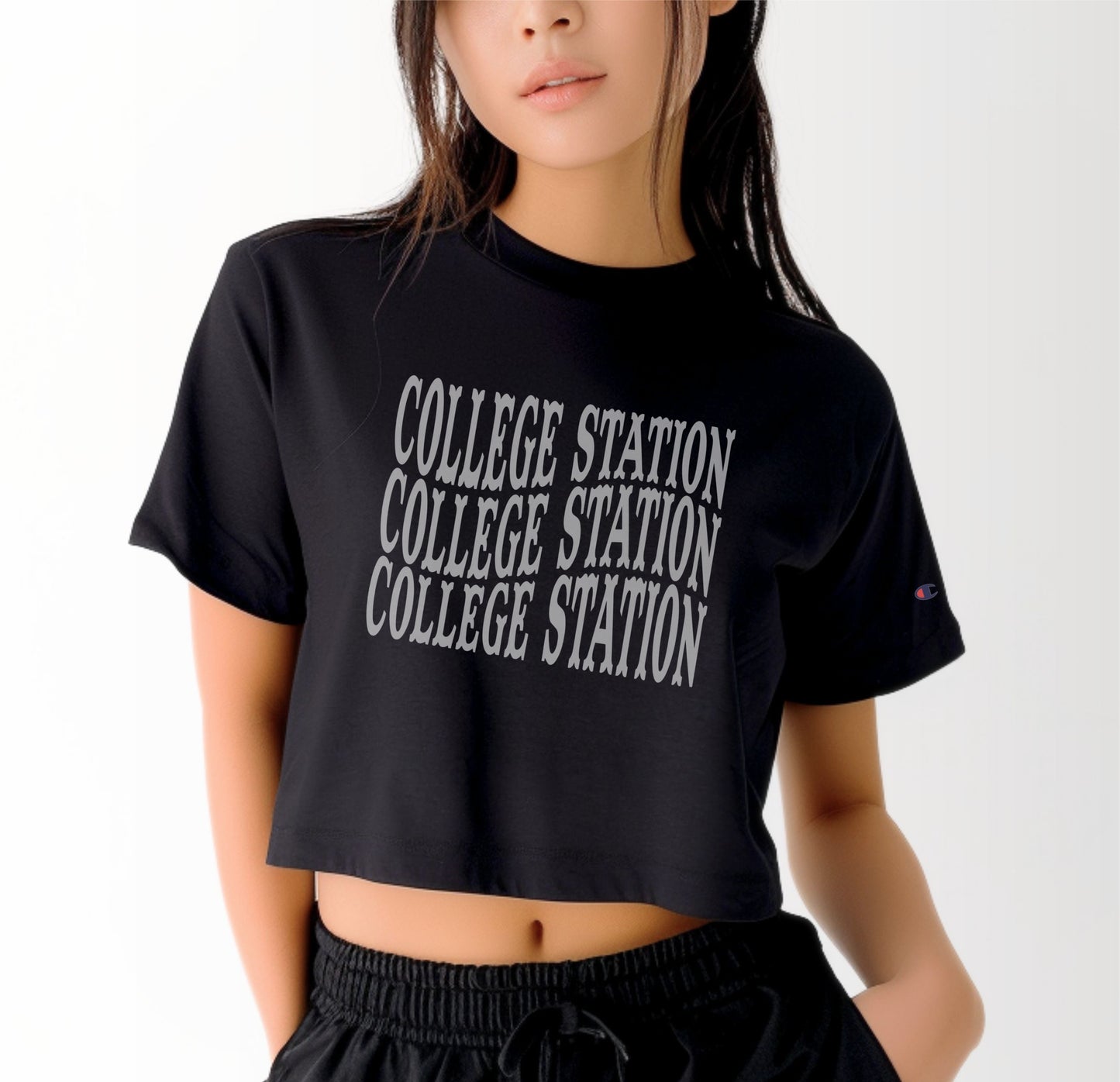 A model wears the Black Adult Womens College Station Western Crop Top.  The ﻿College Station Western﻿ graphic is in bold White in a Western style.