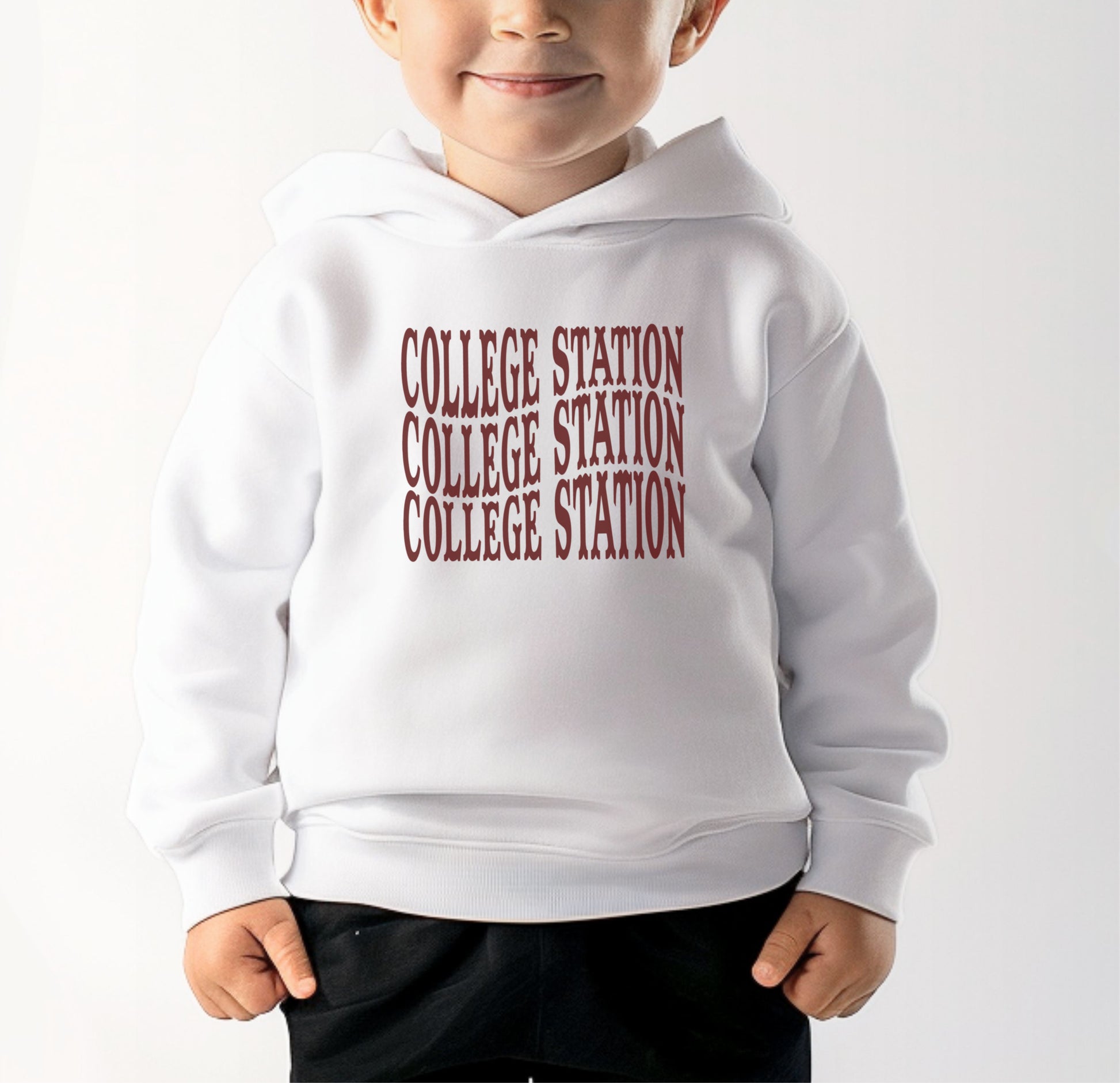 A model wears the White Toddler Unisex College Station Western Hooded Sweatshirt.  The ﻿College Station Western﻿ graphic is in bold Maroon in a Western style.