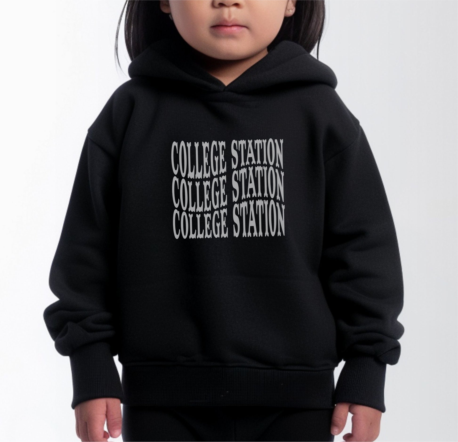 A model wears the Black Toddler Unisex College Station Western Hooded Sweatshirt.  The ﻿College Station Western﻿ graphic is in bold White in a Western style.