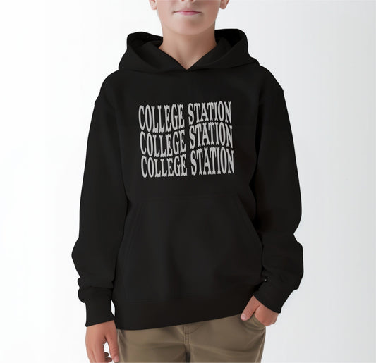 A model wears the Black Youth Unisex College Station Western Hooded Sweatshirt.  The ﻿College Station Western﻿ graphic is in bold White in a Western style.