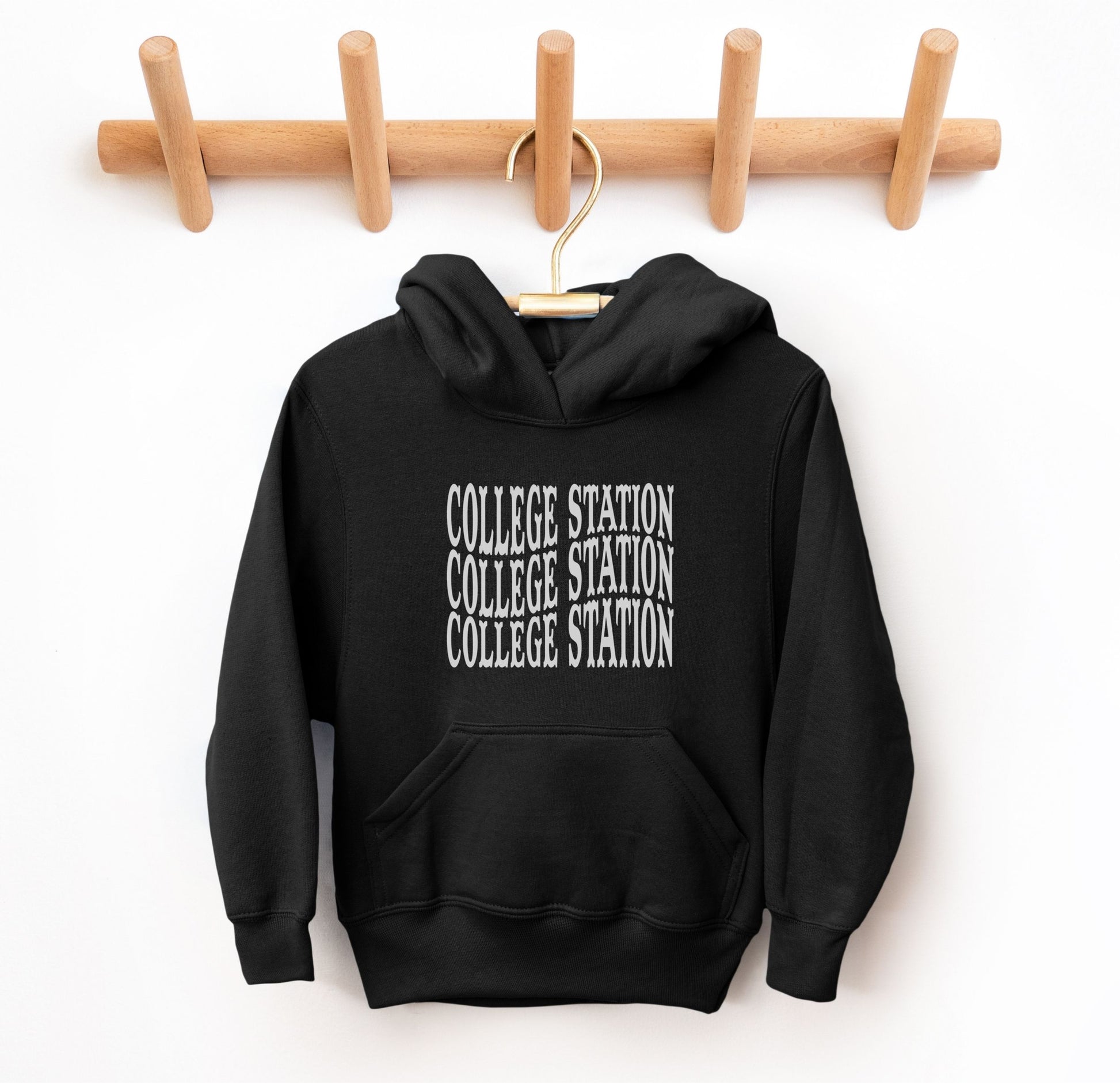 The Black Youth Unisex College Station Western Hooded Sweatshirt lays flat on a white background. The ﻿College Station Western﻿ graphic is in bold White in a Western style.