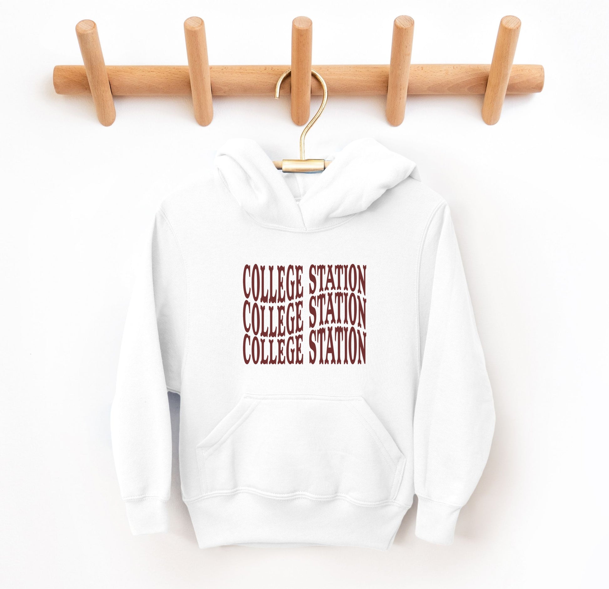 The White Youth Unisex College Station Western Hooded Sweatshirt lays flat on a white background. The ﻿College Station Western﻿ graphic is in bold Maroon in a Western style.