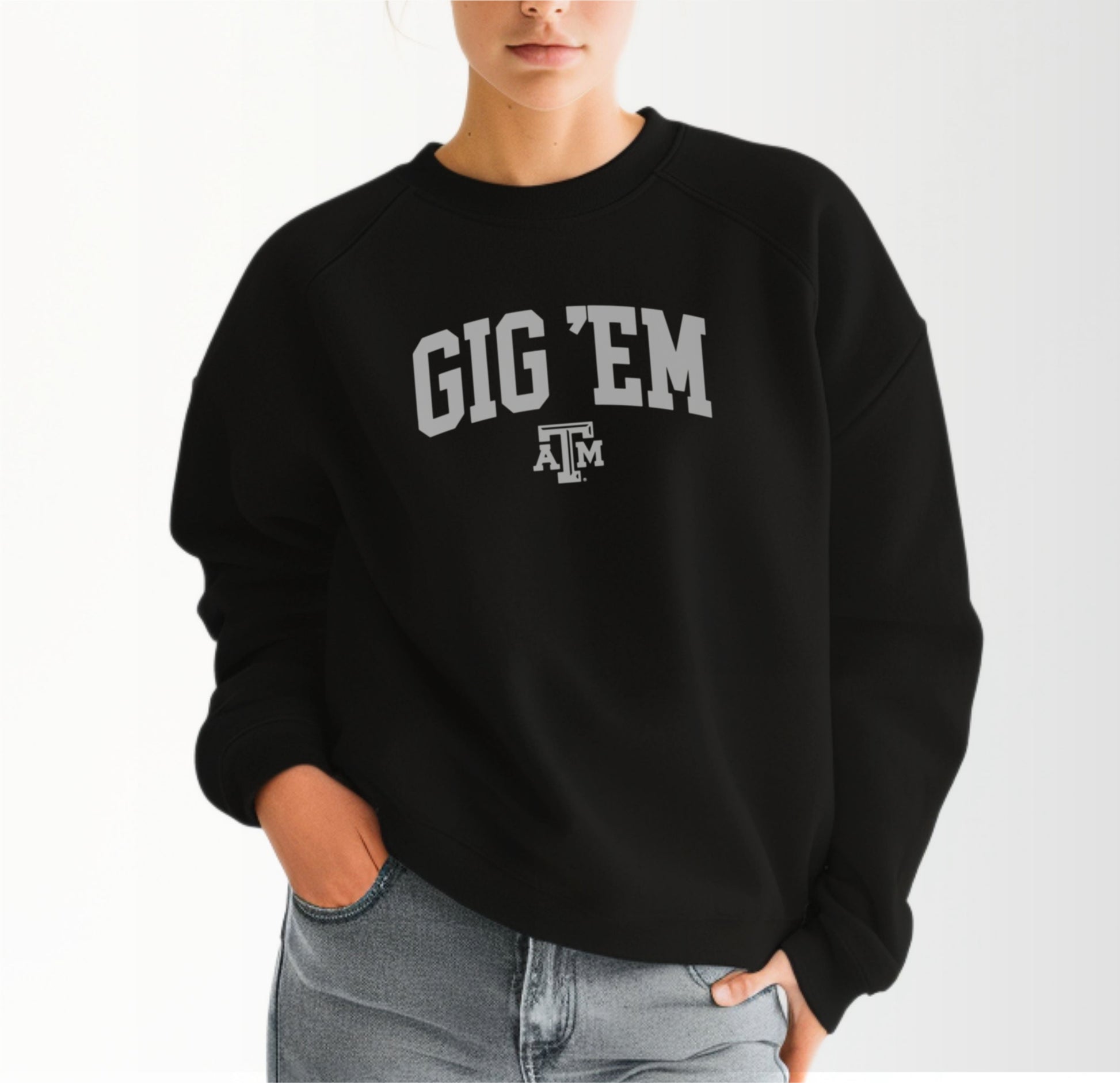 A model wears the Black Adult Unisex Texas A&M Gig 'Em Collegiate Crewneck Sweatshirt.  The ﻿Texas A&M Gig 'Em Collegiate﻿ graphic is in bold White in a Collegiate style.