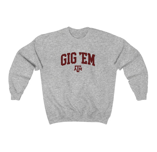 The Sport Grey Adult Unisex Texas A&M Gig 'Em Collegiate Crewneck Sweatshirt lays flat on a white background. The ﻿Texas A&M Gig 'Em Collegiate﻿ graphic is in bold Maroon in a Collegiate style.