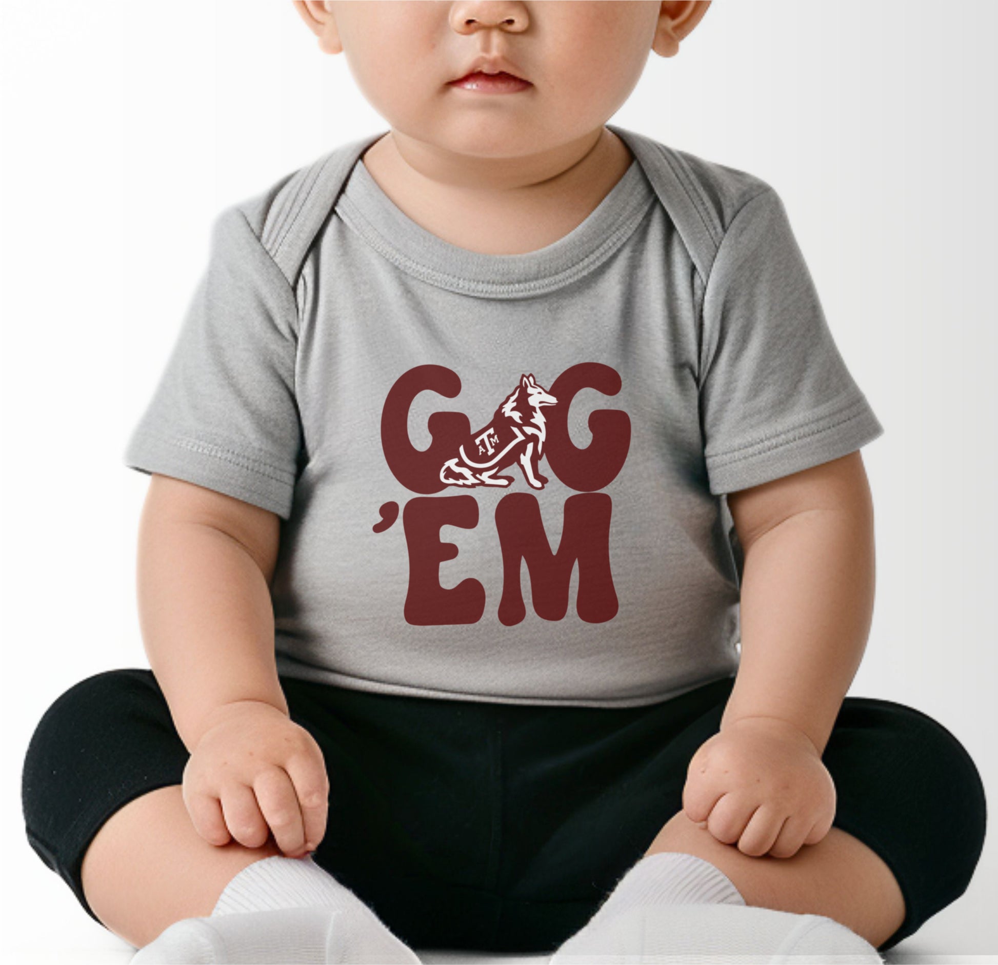 A model wears the Black Infant Unisex Texas A&M Gig 'Em Retro Reveille Bodysuit.  The ﻿Texas A&M Gig 'Em Retro Reveille﻿ graphic is in bold White in a Groovy Vintage style.