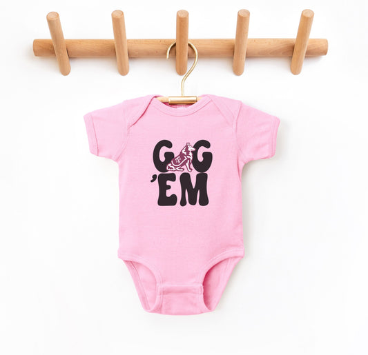 The Pink Infant Unisex Texas A&M Gig 'Em Retro Reveille Bodysuit lays flat on a white background. The ﻿Texas A&M Gig 'Em Retro Reveille﻿ graphic is in bold Maroon in a Groovy Vintage style.