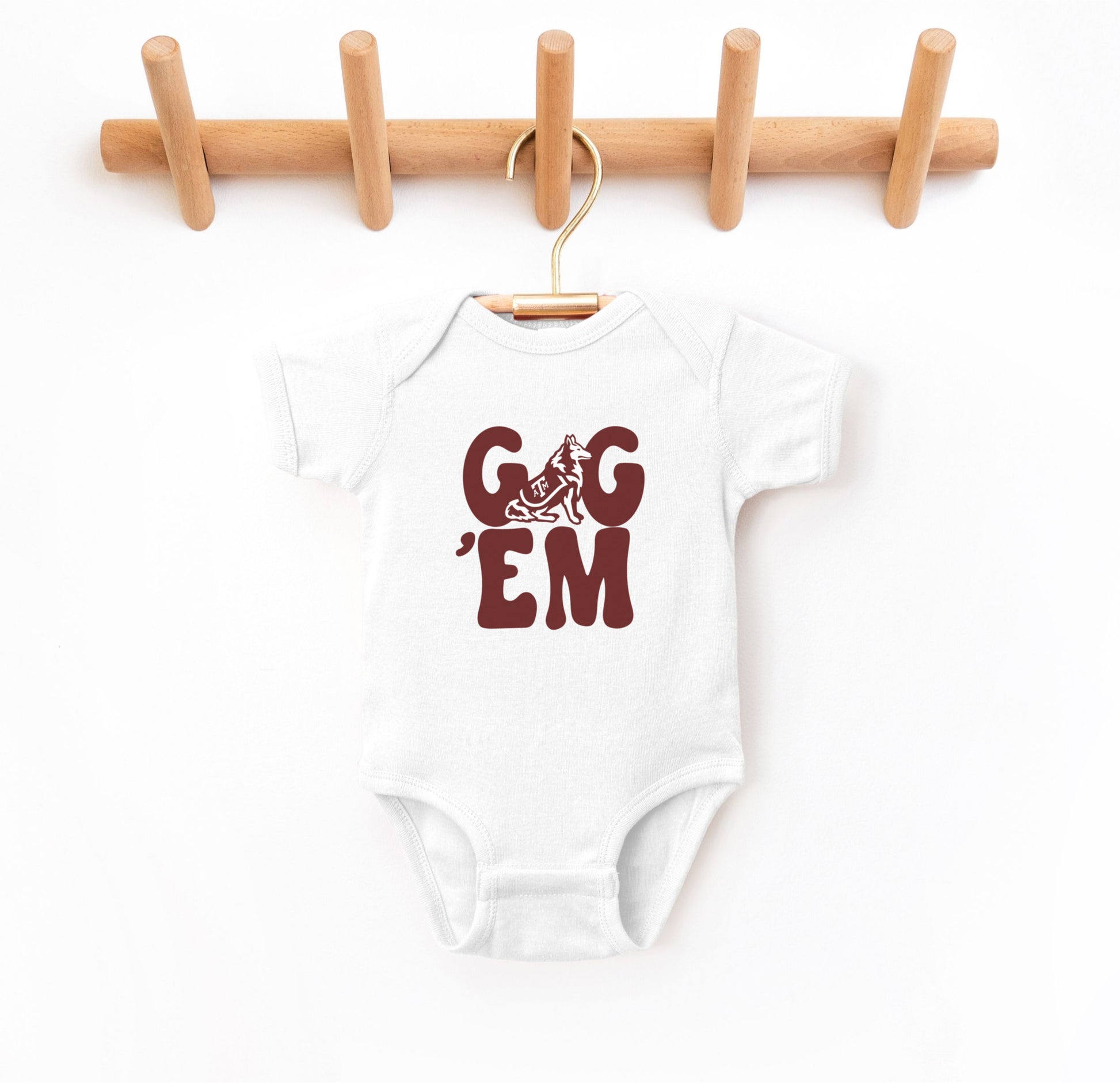 The White Infant Unisex Texas A&M Gig 'Em Retro Reveille Bodysuit lays flat on a white background. The ﻿Texas A&M Gig 'Em Retro Reveille﻿ graphic is in bold Maroon in a Groovy Vintage style.