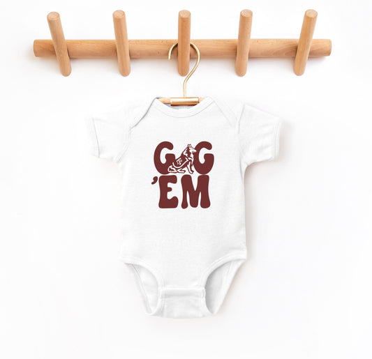 The White Infant Unisex Texas A&M Gig 'Em Retro Reveille Bodysuit lays flat on a white background. The ﻿Texas A&M Gig 'Em Retro Reveille﻿ graphic is in bold Maroon in a Groovy Vintage style.