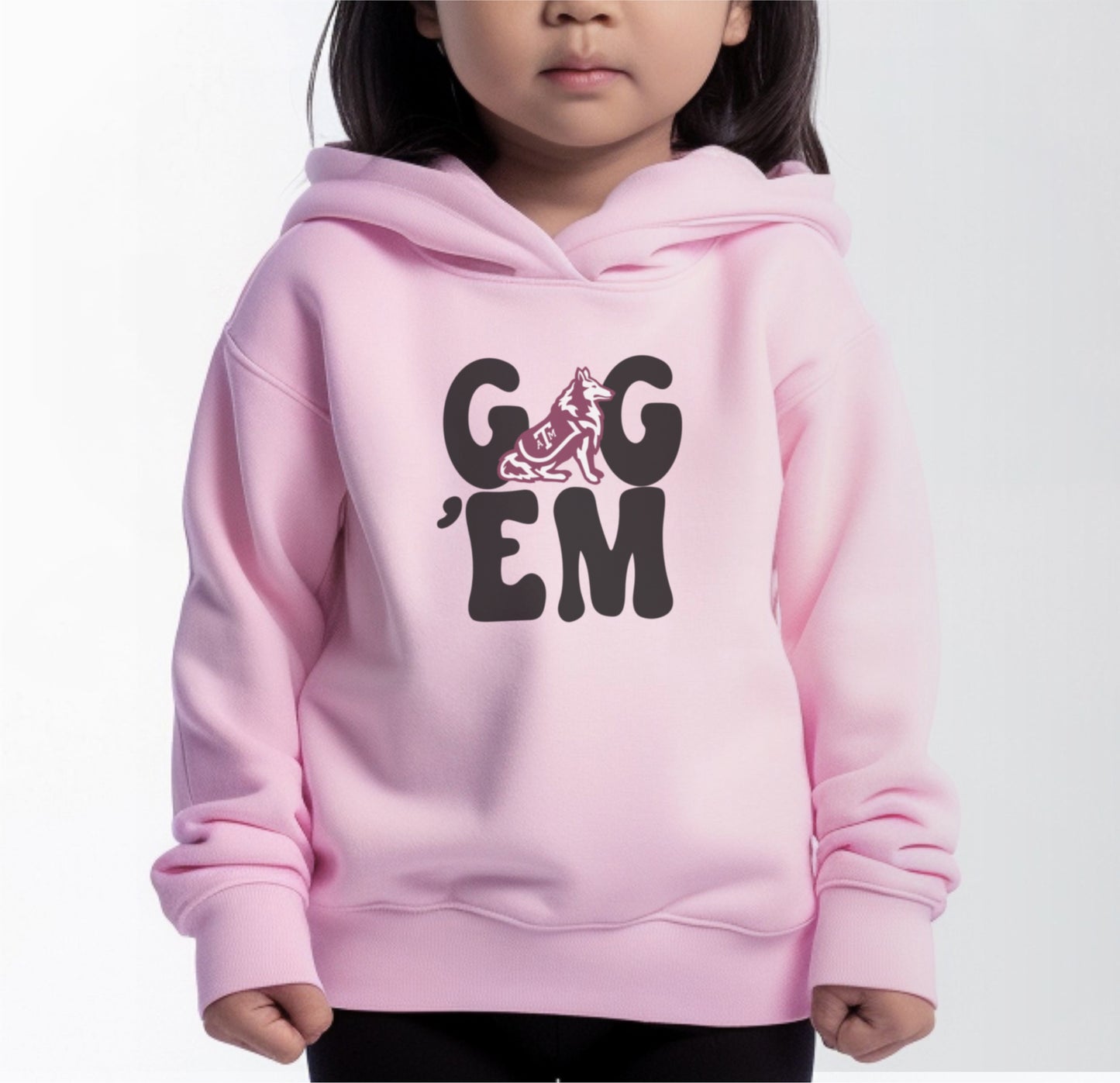 A model wears the Pink Toddler Unisex Texas A&M Gig 'Em Retro Reveille Hooded Sweatshirt.  The ﻿Texas A&M Gig 'Em Retro Reveille﻿ graphic is in bold White in a Groovy Vintage style.