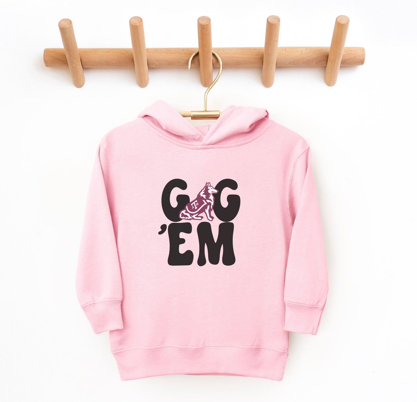 The Pink Toddler Unisex Texas A&M Gig 'Em Retro Reveille Hooded Sweatshirt lays flat on a white background. The ﻿Texas A&M Gig 'Em Retro Reveille﻿ graphic is in bold White in a Groovy Vintage style.