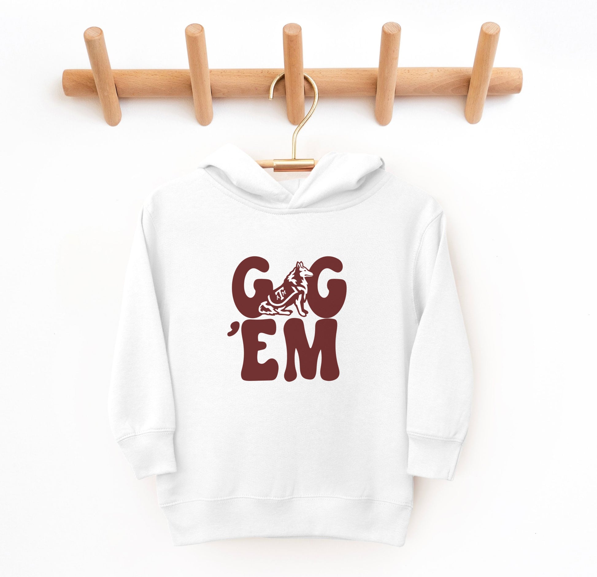 The White Toddler Unisex Texas A&M Gig 'Em Retro Reveille Hooded Sweatshirt lays flat on a white background. The ﻿Texas A&M Gig 'Em Retro Reveille﻿ graphic is in bold Maroon in a Groovy Vintage style.