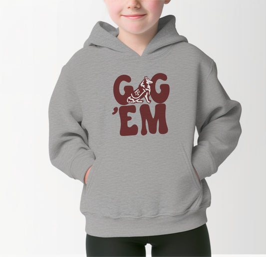 A model wears the Sport Grey Youth Unisex Texas A&M Gig 'Em Retro Reveille Hooded Sweatshirt.  The ﻿Texas A&M Gig 'Em Retro Reveille﻿ graphic is in bold Maroon in a Groovy Vintage style.