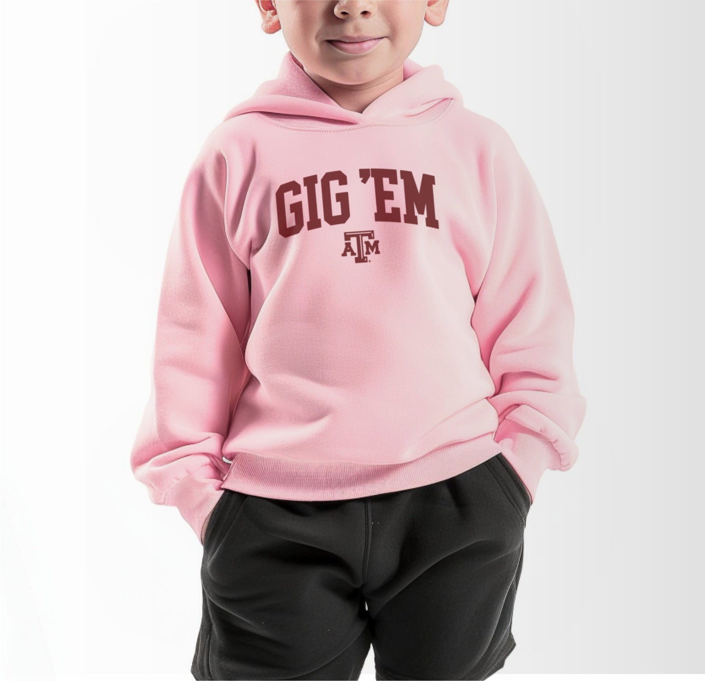 A model wears the Pink Toddler Unisex Texas A&M Gig 'Em Collegiate Hooded Sweatshirt.  The ﻿Texas A&M Gig 'Em Collegiate﻿ graphic is in bold White in a Collegiate style.