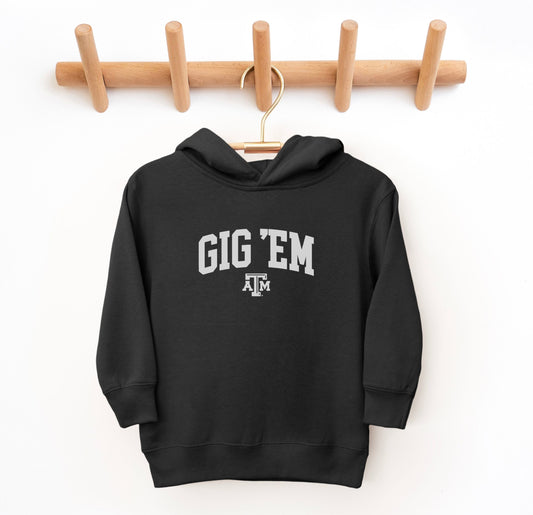 The Black Toddler Unisex Texas A&M Gig 'Em Collegiate Hooded Sweatshirt lays flat on a white background. The ﻿Texas A&M Gig 'Em Collegiate﻿ graphic is in bold White in a Collegiate style.