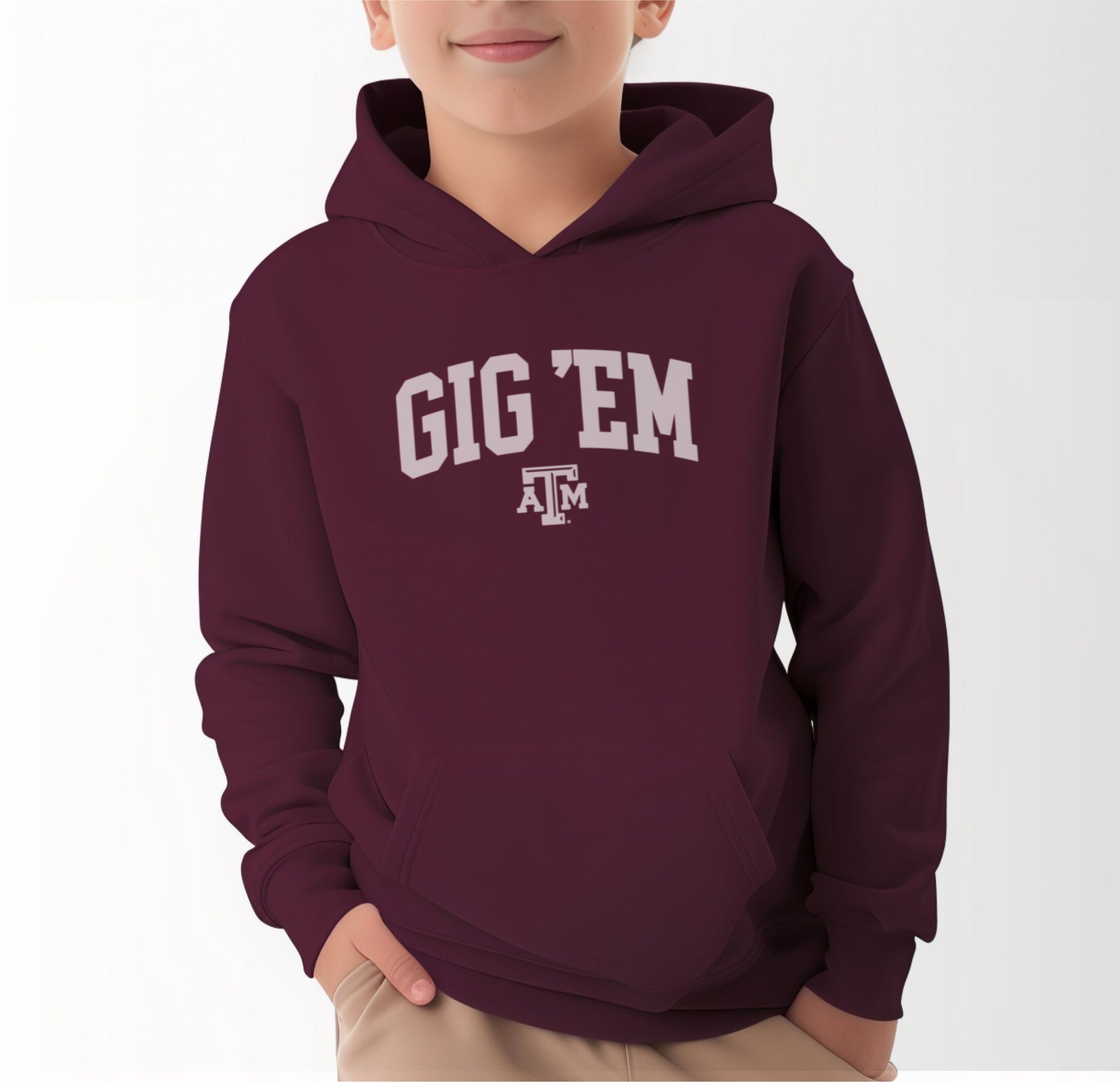 A model wears the Maroon Youth Unisex Texas A&M Gig 'Em Collegiate Hooded Sweatshirt.  The ﻿Texas A&M Gig 'Em Collegiate﻿ graphic is in bold White in a Collegiate style.