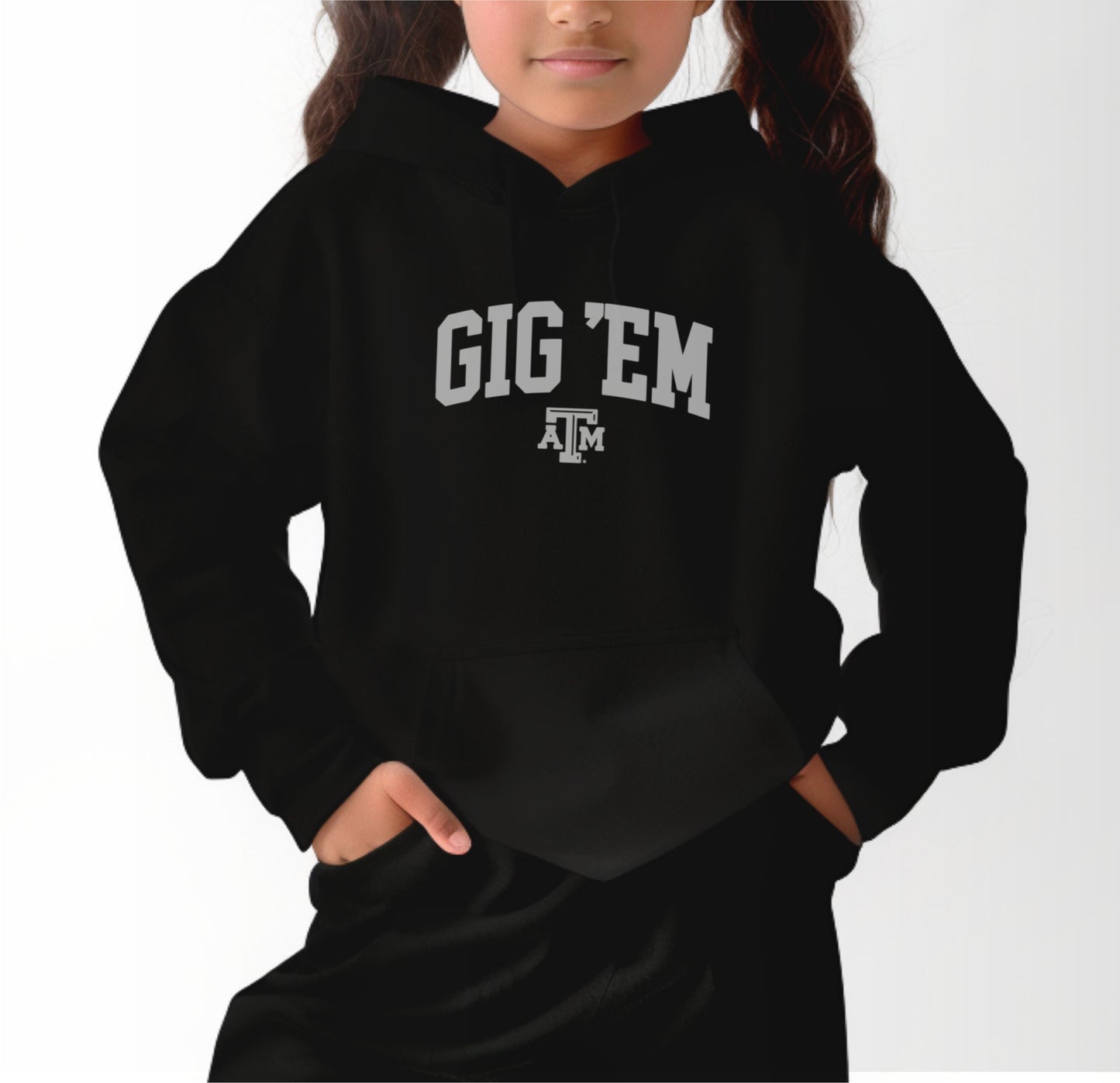 A model wears the Black Youth Unisex Texas A&M Gig 'Em Collegiate Hooded Sweatshirt.  The ﻿Texas A&M Gig 'Em Collegiate﻿ graphic is in bold White in a Collegiate style.